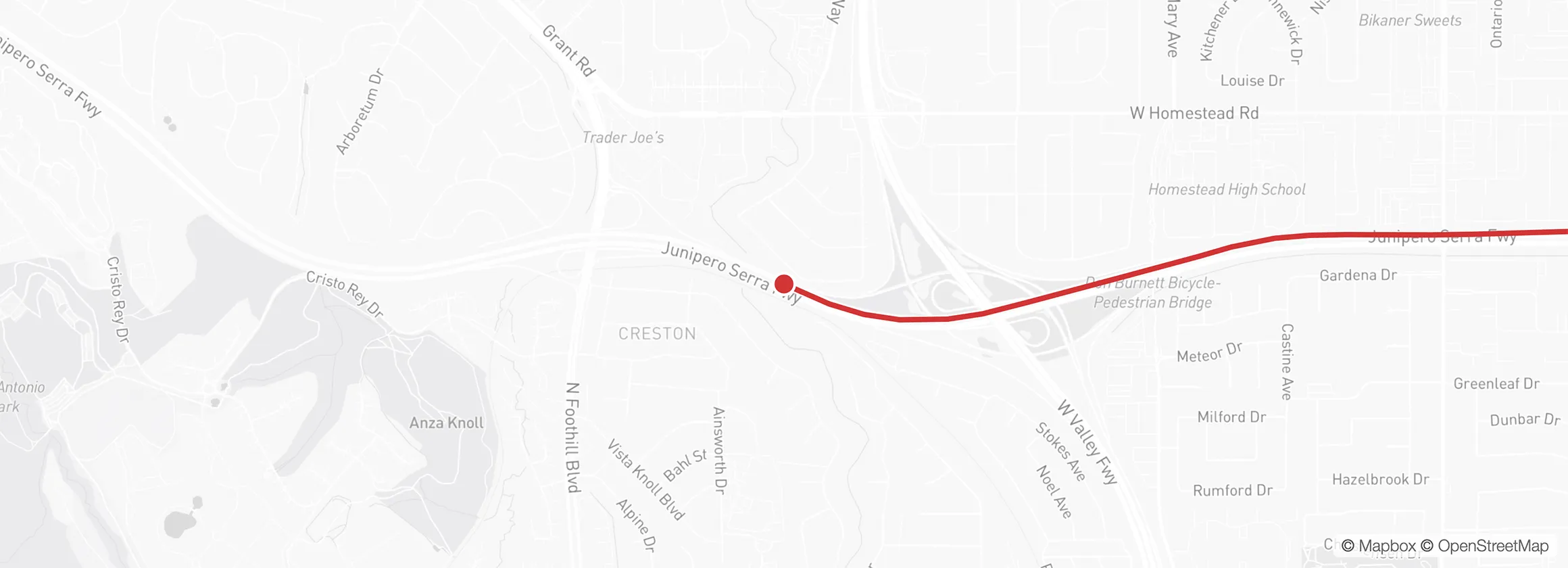This screenshot shows a live location view: a simple map with a highlighted red path along the Junipero Serra Freeway in California, marking recent movement. A circular marker indicates the current position on the route, giving real-time tracking.